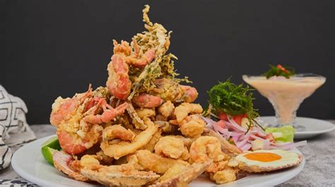 Fotografía gastronómica de un plato de Jalea Mixta con mariscos y salsas peruanas
