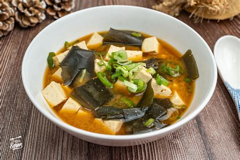 Ingredientes frescos para una sopa de miso reconfortante: verduras variadas, tofu, algas y pasta de miso.