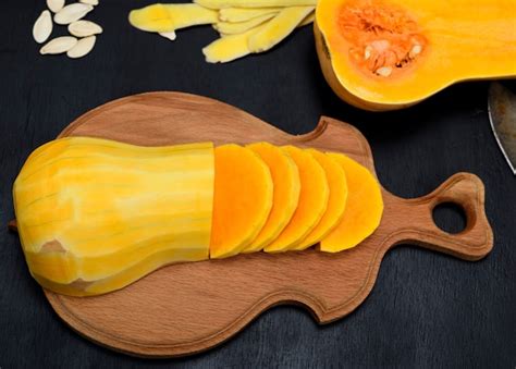 Tablilla de madera con calabaza pelada y troceada junto a otros ingredientes como cebolla y ajo