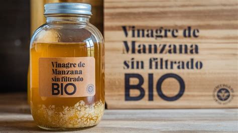 Botellas de vinagre sin filtrar en un estante oscuro y fresco, destacando el etiquetado.