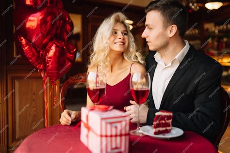 Pareja brindando junto a una tarta pequeña con decoraciones románticas