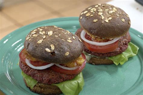 Fotografía profesional de una hamburguesa vegetariana de betabel montada sobre pan artesanal con vegetales frescos.