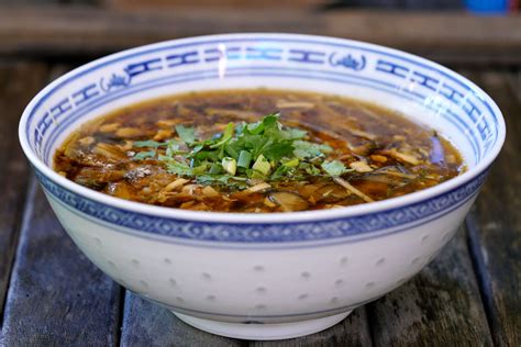 Imagen de un tazón humeante de sopa agripicante, mostrando los ingredientes característicos como tofu y brotes de bambú.