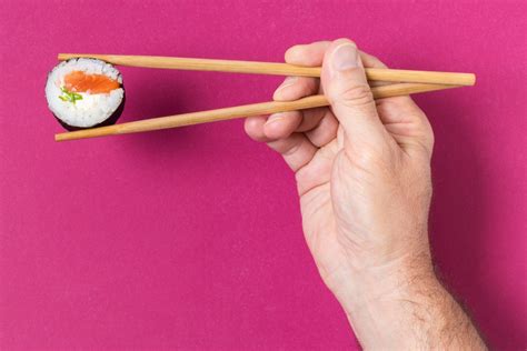 Ilustración detallada sobre cómo sujetar los palillos para comer sushi.