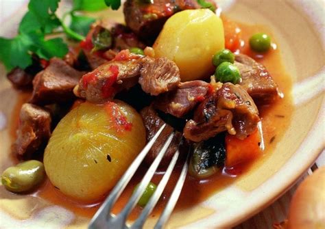 Plato principal de cazuela de cordero con habas y guisantes, bien presentado