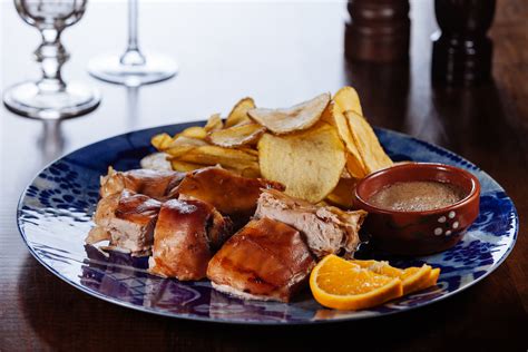 Leitão assado à Bairrada cortado en porciones en un plato, mostrando la piel crujiente y la carne tierna