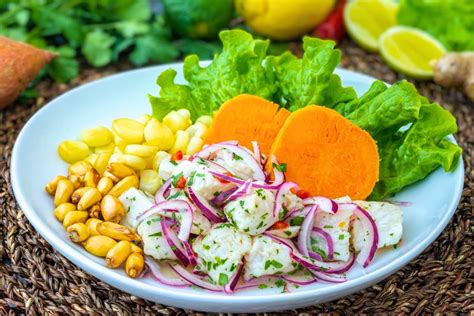 Plato de ceviche peruano tradicional con sus guarniciones clásicas de camote, choclo y canchita