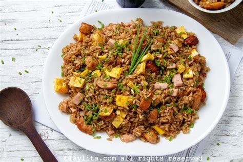 Fotografía de un plato de arroz chaufa peruano humeante en un wok, con trozos de pollo, tortilla de huevo y cebolla china