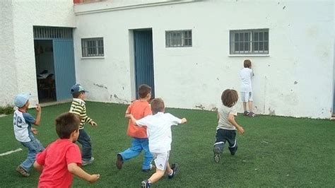 Niños jugando al Pollito Inglés en un parque, uno de espaldas a la pared y los otros avanzando