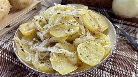 Fotografía de patatas al horno aliñadas con cebolla y limón.