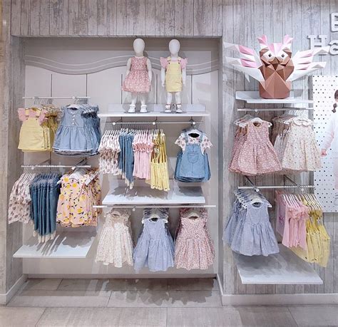 Fotografía de una tienda de ropa infantil con exhibidores de ropa de bebé.