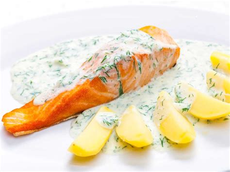 Plato de salmón a la plancha acompañado de una cremosa salsa de yogur y eneldo con rodajas de limón frescas