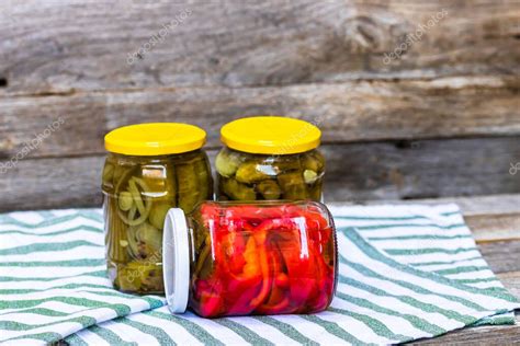 Fotografía profesional de frascos de vidrio con pimientos rojos en aceite y dientes de ajo, iluminación cálida de cocina rústica