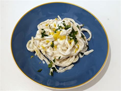 Foto de un plato de pasta con ricotta y limón adornado con parmesano y albahaca