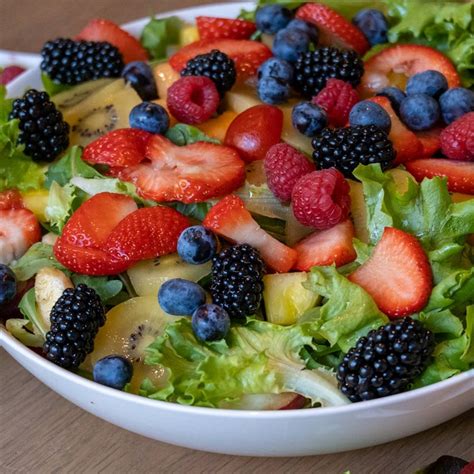 Imagen de una ensalada colorida con frutas, frutos secos y queso.