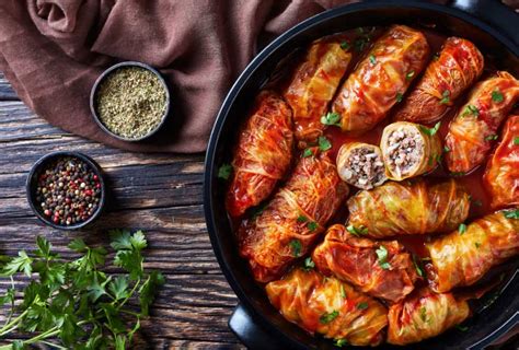 Variedad de platos tradicionales rumanos, incluyendo sarmale, mici, plăcintă y cozonac.