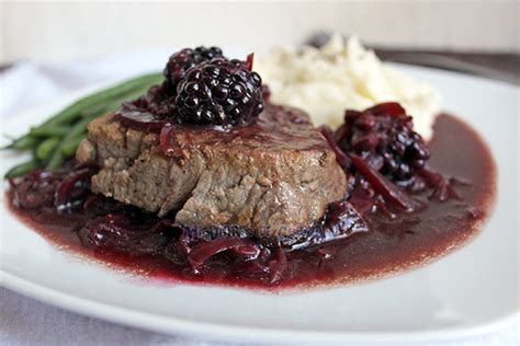 Plato artístico de filete de res con una vibrante salsa de moras y reducción de cabernet.