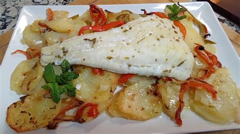 Plato de merluza a la vasca servido con patatas panaderas y pimientos verdes