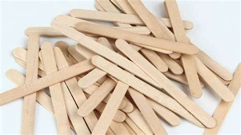 Suministros para manualidades con palitos de helado, incluyendo palitos, pegamento, pinturas, pompones y ojos móviles.