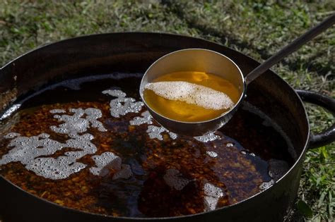 Una batidora de brazo en acción dentro de una olla con mermelada espesa.