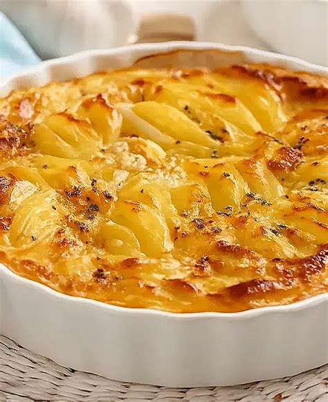 Fotografía gastronómica de un gratin de papas con una textura dorada y uniforme en una fuente de cerámica.