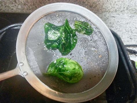 Esquema paso a paso: desde el lavado de las hojas de espinaca hasta el salteado con ajo en la sartén.