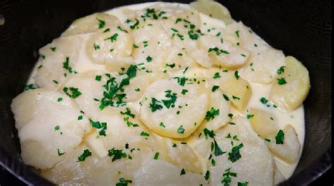Capas de papas, crema y queso en un molde para gratinar