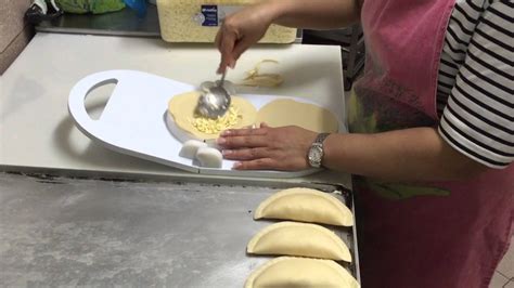 Demostración visual del proceso de doblar y sellar las empanadas, incluyendo el uso del tenedor y los cortes para el vapor.