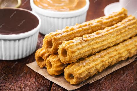 Imagen de churros recién fritos y dorados con azúcar y canela, acompañados de sirope de chocolate