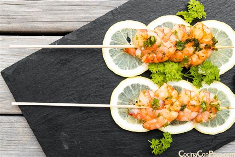 Imagen de brochetas de langostinos cocinándose a la plancha.