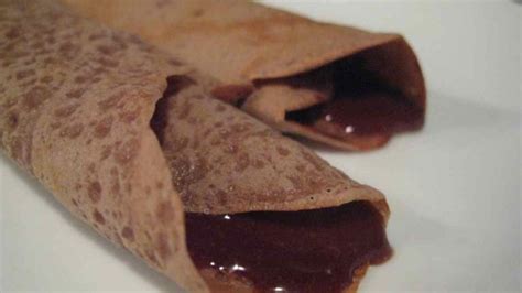 Imagen de crepes de vino tinto y chocolate servidas con azúcar moreno espolvoreado.