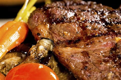 Plato de ojo de bife al horno servido con guarnición de vegetales asados y hierbas frescas