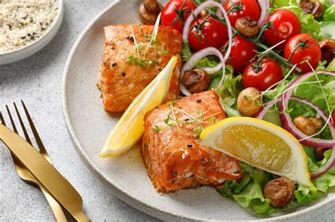 Fotografía de un plato con dos rodajas de salmón frito y una ensalada colorida al lado.
