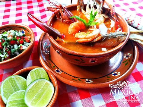 Fotografía gastronómica de un caldo de mariscos humeante con hierbas frescas y mariscos variados servido en un tazón de greda
