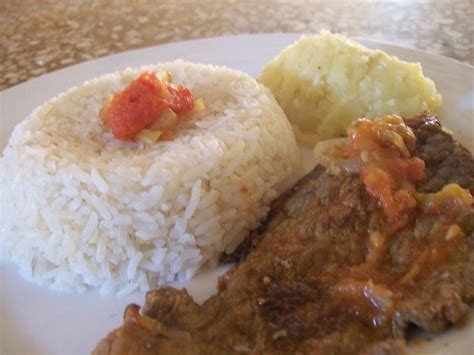 Imagen de un plato servido de bistec encebollado con cebollas caramelizadas y guarnición de arroz.