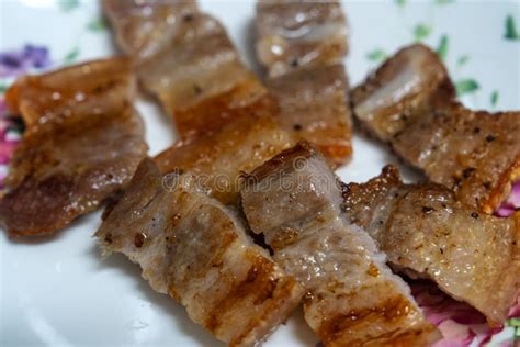 Fotografía gastronómica de lonchas de panceta dorándose en una plancha de hierro fundido.