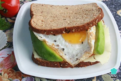 Proceso de montaje de sándwich con capas de aguacate, salmón y huevo