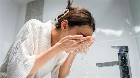 Primer plano de una persona lavándose la cara con agua fría.